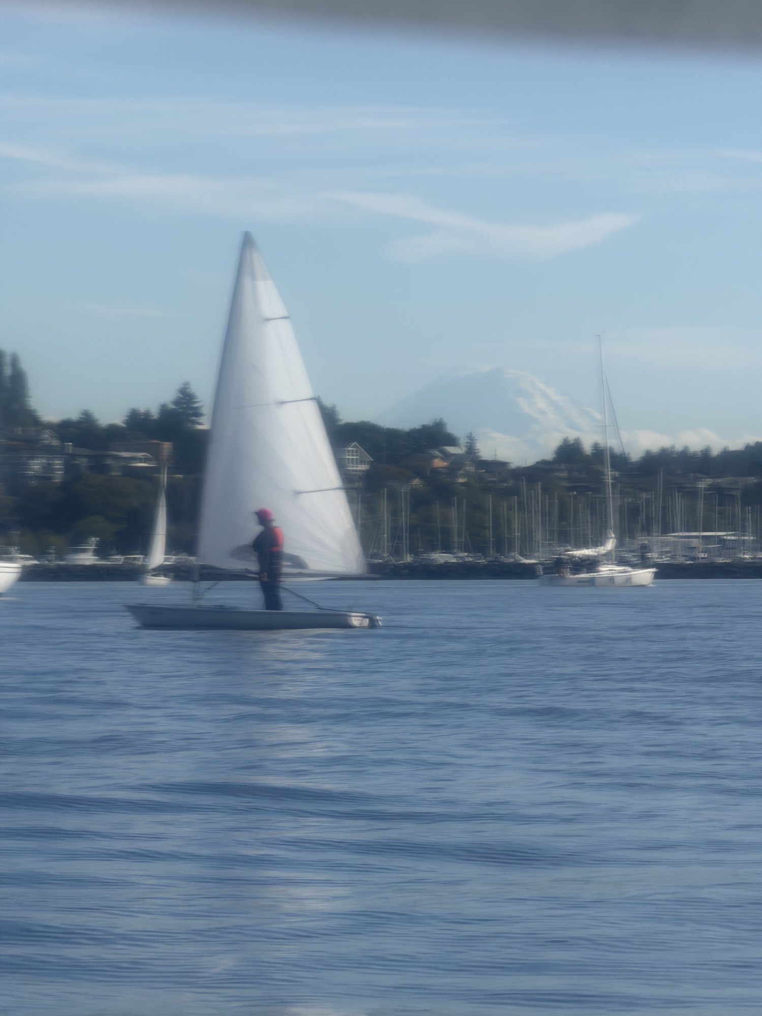 A sailor standing in a Laser in very light wind, with Mount Rainier in the background