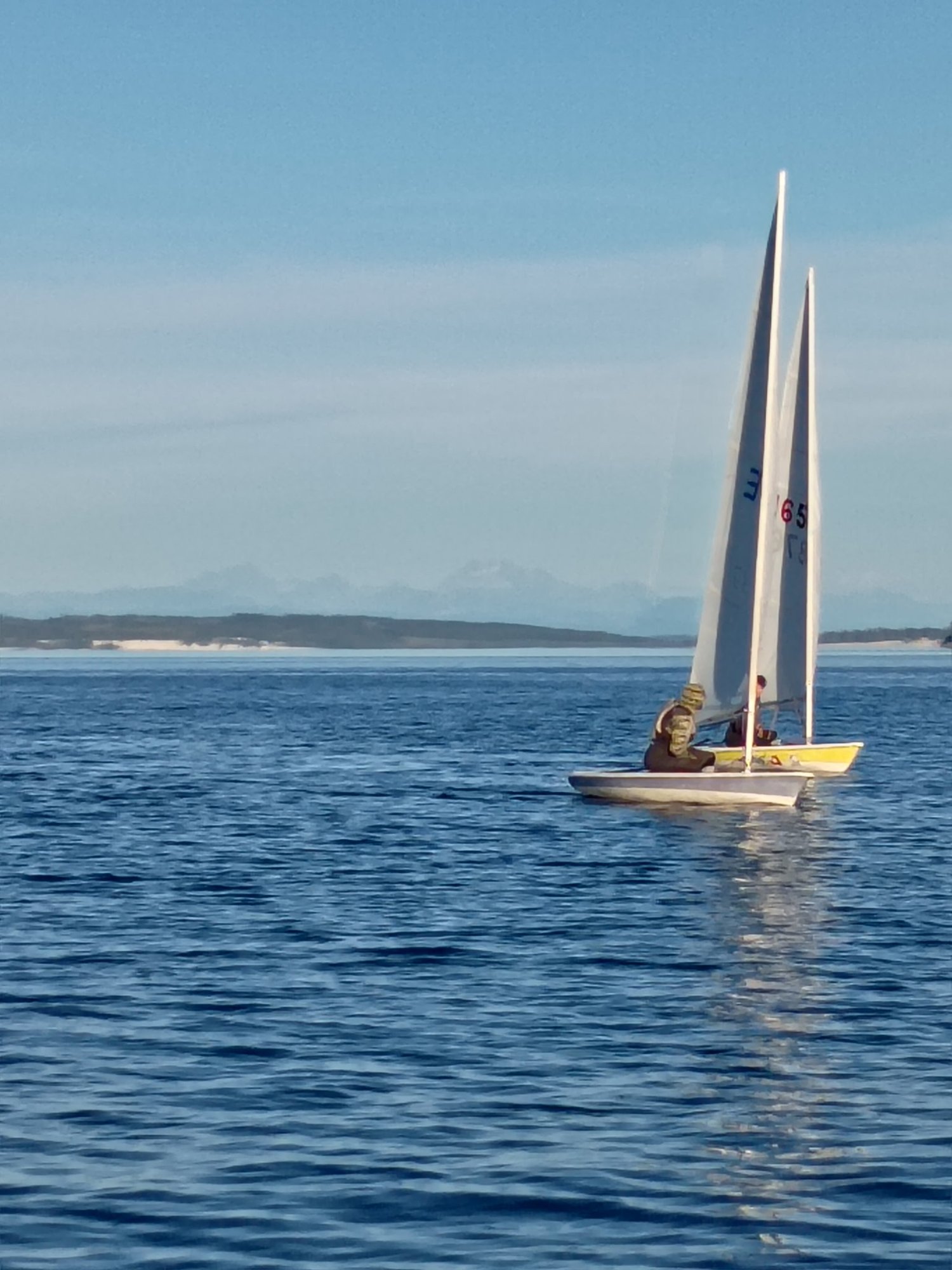 Two Lasers sailing side by side on open water