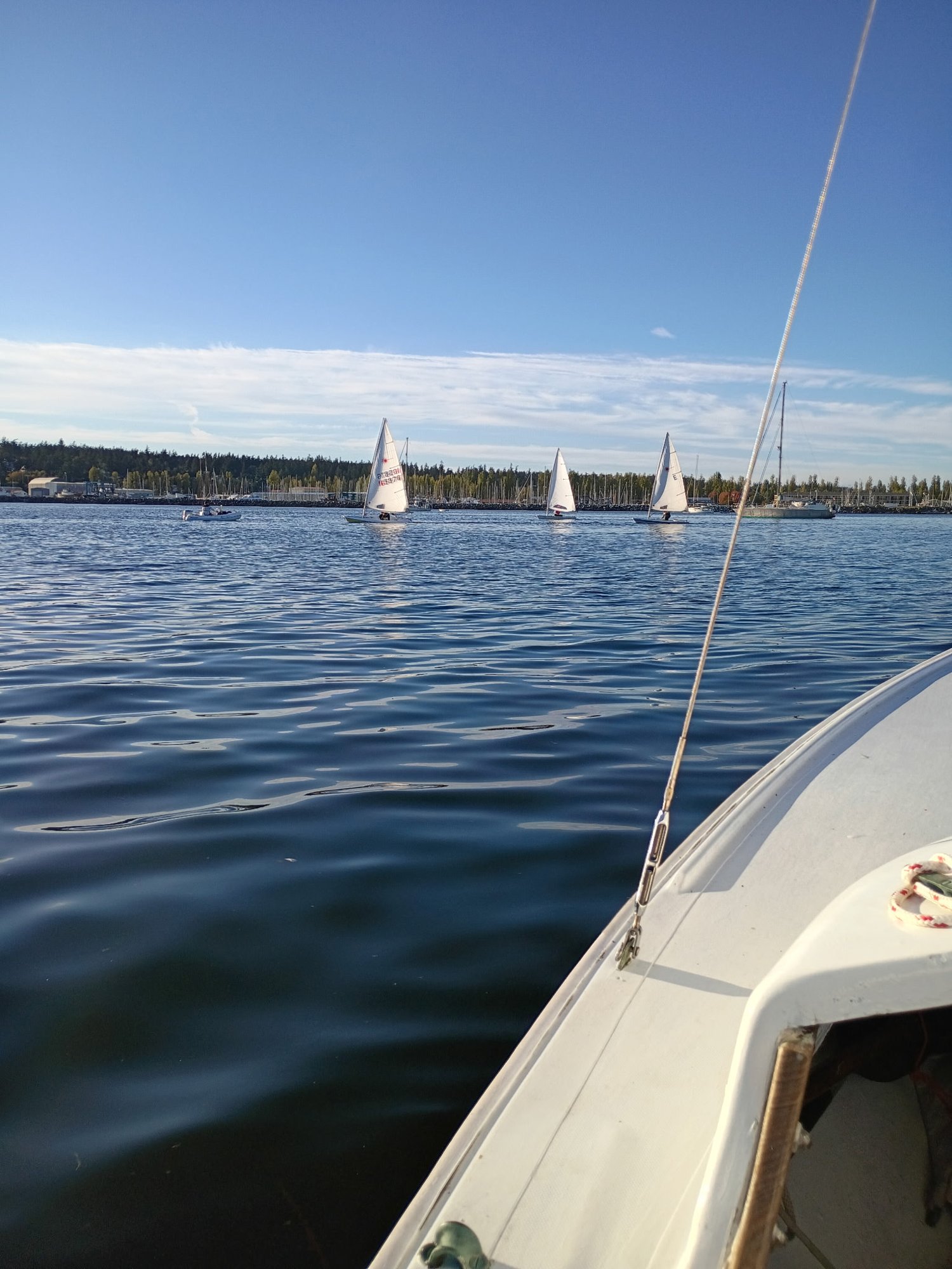 Three Lasers sailing on Port Townsend Bay, seen from a boat